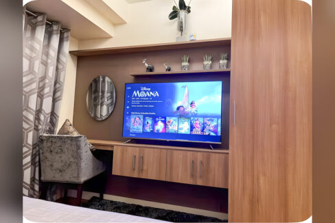 TV wall with floating shelves, wood-grain cabinets, round mirror and velvet chair