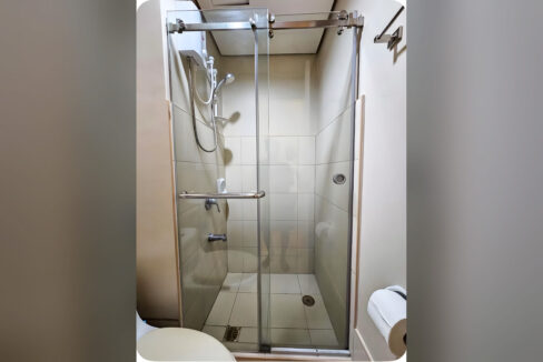 Sliding glass shower enclosure with water heater and handheld shower
