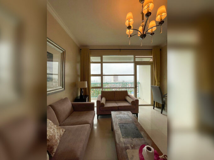 Living room at Citylights Gardens with two sofas, a chandelier and a glass door to the balcony