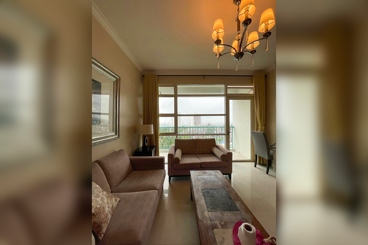 Living room at Citylights Gardens with two sofas, a chandelier and a glass door to the balcony