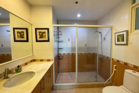 Bathroom with a long marble-top vanity, wide mirror and walk-in glass shower
