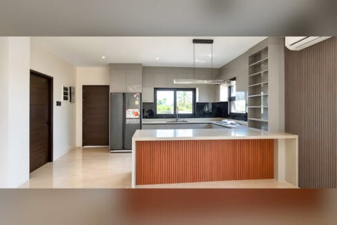 Kitchen with grey high-gloss cabinets, side-by-side refrigerator and fluted wood peninsula