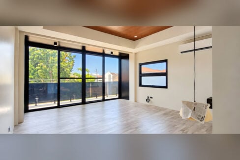 Upstairs bedroom with floor-to-ceiling glass to the balcony and wood-plank ceiling