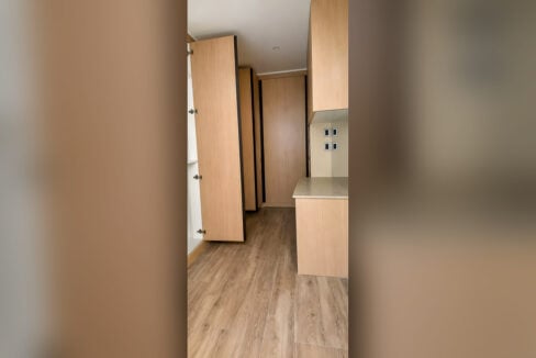 Walk-in closet with full-height wood-grain cabinets and a counter
