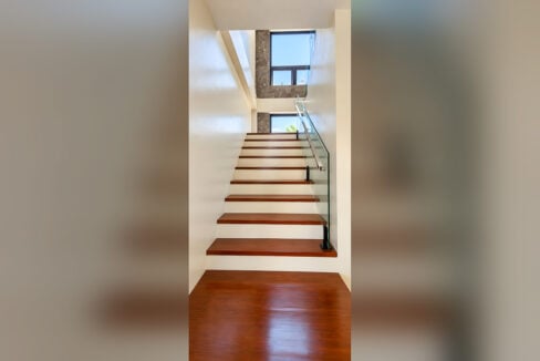 Staircase with wood treads, frameless glass railing and marble-clad window wall