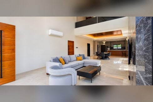 Double-height living room with sectional sofa, split aircon and view to the dining area