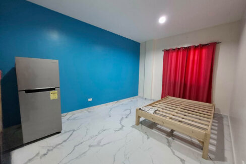 Bedroom with a blue accent wall, red curtains and a compact fridge