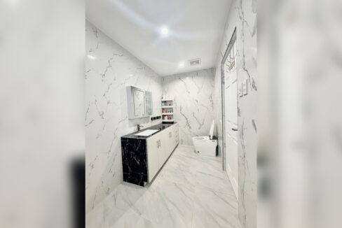Main bathroom with a long vanity and white marble-look tiles