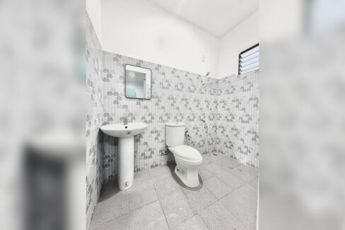 Bathroom with a pedestal sink, mirror and louvered window