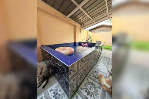 Covered plunge pool clad in black marble-look tile with a patterned floor