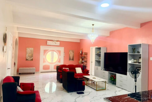 Living room with a coral wall, crystal chandelier and red sofas