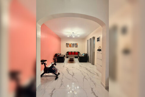 Arched opening to a second lounge with a sofa set and exercise bike