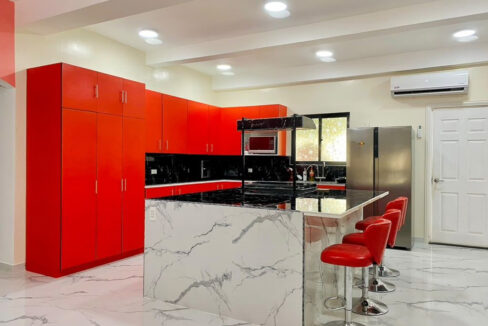 Red-cabinet kitchen with a waterfall island and four bar stools