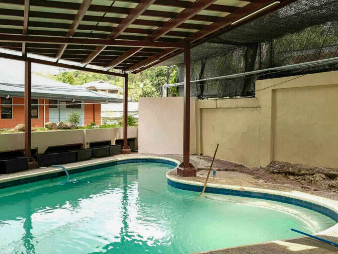 Covered swimming pool under a timber pergola at a Doña Rita Village house in Banilad