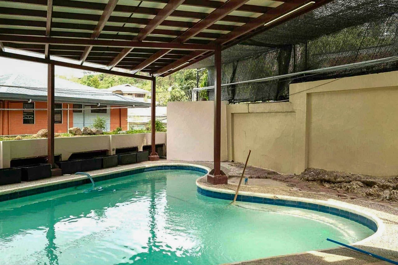 Covered swimming pool under a timber pergola at a Doña Rita Village house in Banilad