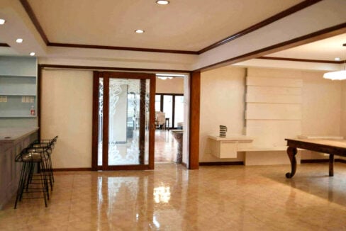 Ground-floor hall with a grey bar counter, wire-frame stools and glossy tile floors