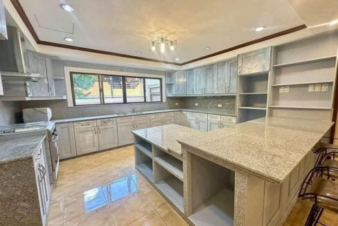 Kitchen with grey shaker cabinets, granite counters and a large granite island