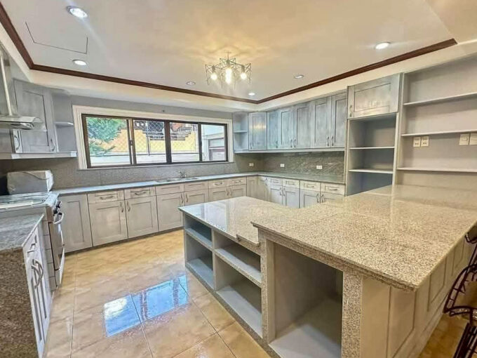 Kitchen with grey shaker cabinets, granite counters and a large granite island