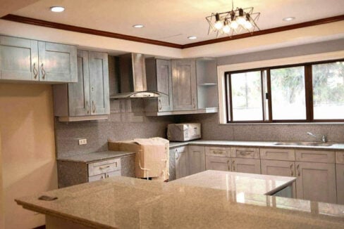 Kitchen corner with a stainless chimney hood, granite backsplash and wide window