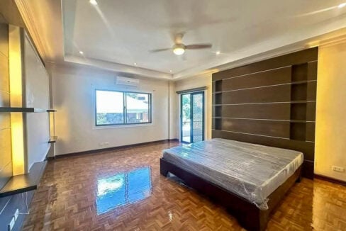 Bedroom with herringbone parquet floors, a wood-panel headboard wall and balcony door