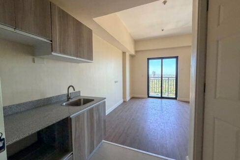 Kitchenette with wood-grain cabinets and a granite counter facing the balcony door