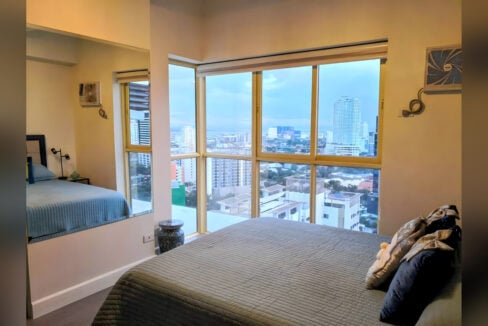 Master bedroom with floor-to-ceiling corner windows over the city and the sea
