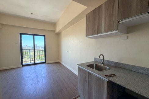 Kitchenette with wood-grain cabinets and a granite counter beside the balcony door