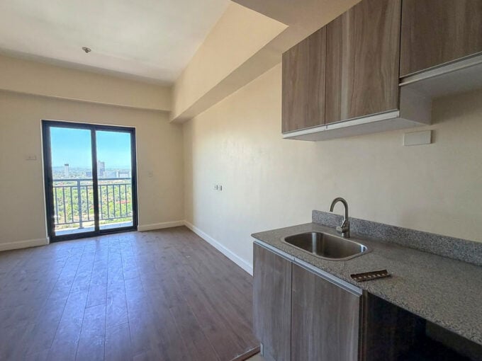 Kitchenette with wood-grain cabinets and a granite counter beside the balcony door