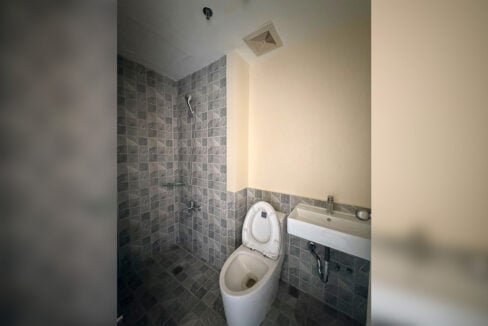 Bathroom with grey stone-look tiles, handheld shower and wall-hung basin