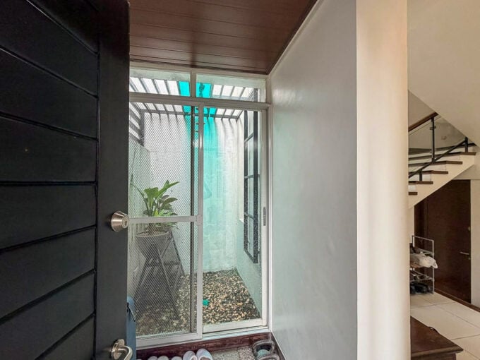 Front entry beside a glass-enclosed indoor garden in a furnished house for sale in Banilad