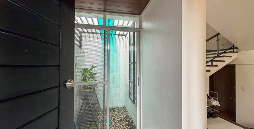 Front entry beside a glass-enclosed indoor garden in a furnished house for sale in Banilad