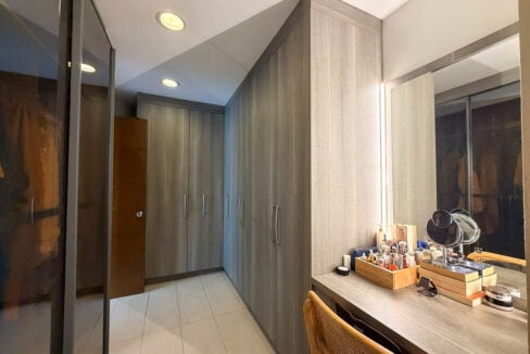 Walk-in closet with built-in wardrobes and lit vanity mirror