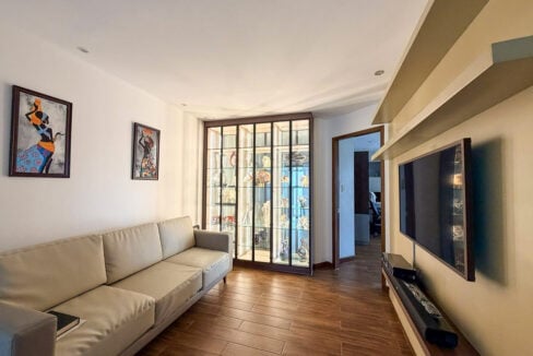 Family room with lit glass display cabinet and wall-mounted TV