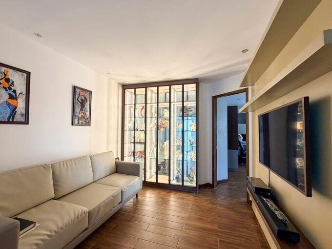 Family room with lit glass display cabinet and wall-mounted TV