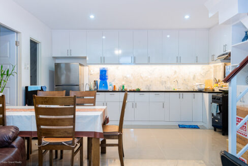 L-shaped kitchen with white high-gloss cabinets, black granite counter and gas range