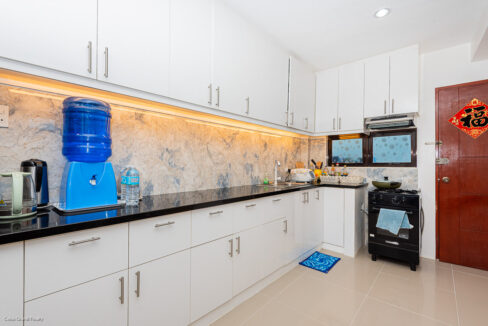 Kitchen counter with a lit marble-look backsplash, range hood and freestanding gas range