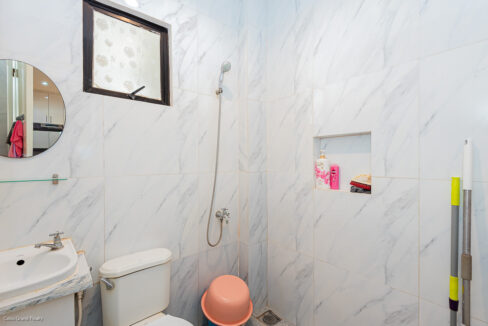 Ground-floor bathroom with marble-look tiles, hand shower and round mirror
