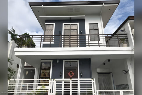 Front of the house with grey and white walls, dark balcony railing and wall lanterns