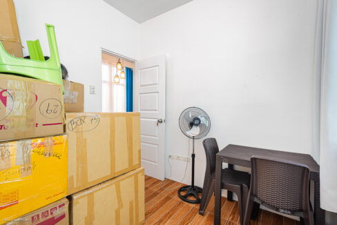 Bedroom with a standing fan, small table and chairs by the window