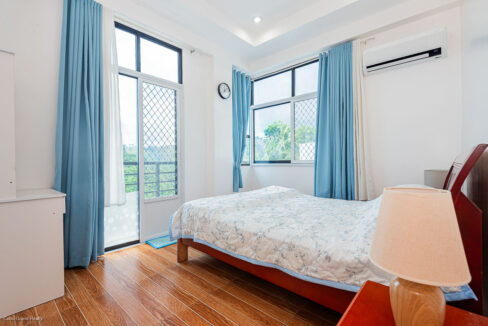 Bedroom with a double bed, blue drapes and a glass door opening to the balcony