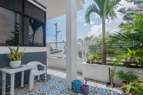 Front patio with patterned tiles, a small table and planters along the fence