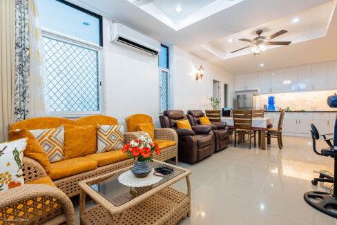 Open living and dining area with a rattan sofa set, leather recliners and white kitchen cabinets