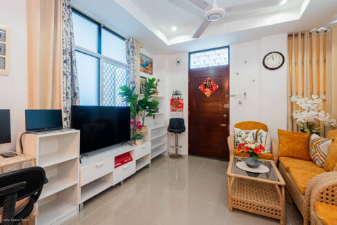 Living room with a TV console, built-in shelves and the wooden front door