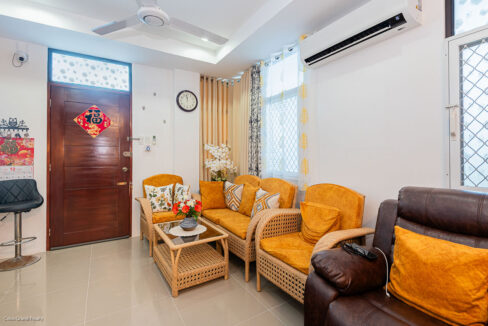 Seating area by the front door with rattan chairs, split-type aircon and a leather recliner