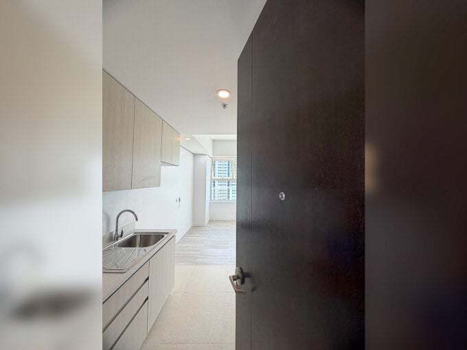 Entry of a One Astra Place studio with galley kitchenette, sink and wood-grain cabinets