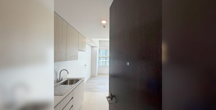 Entry of a One Astra Place studio with galley kitchenette, sink and wood-grain cabinets