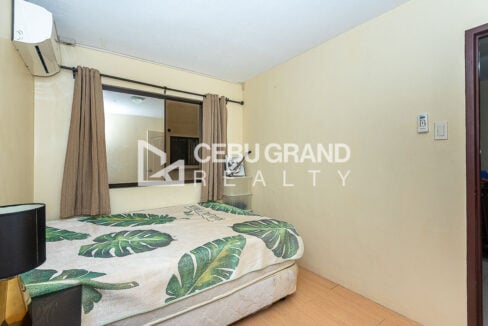 Bedroom window with curtains above the double bed and wood-look floor