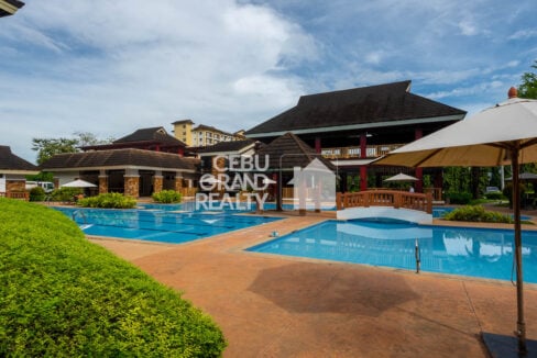 Resort-style pools with a wooden footbridge beside the One Oasis clubhouse