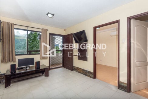 Living area with a window over the trees, media console and security screen door