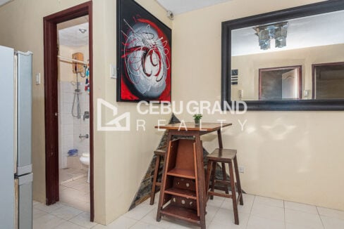 Bar-height dining table with two stools beside the bathroom door